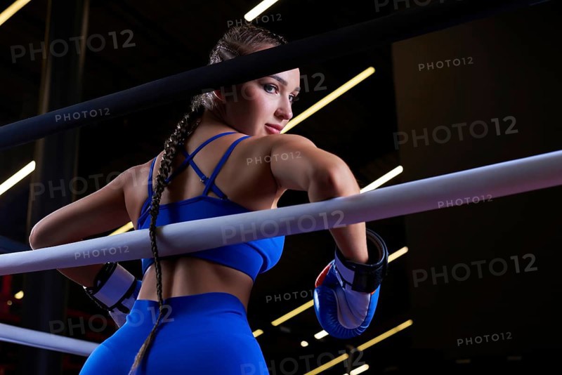 Powerful charged girl stands in the corner of the ring and is ready to explode in the next round. The concept of wrestling and boxing. Mixed media