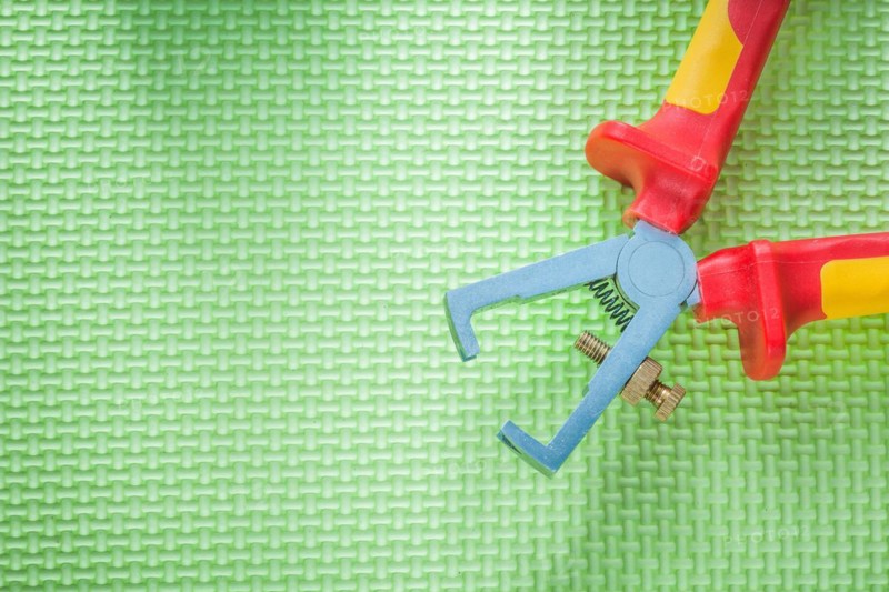 Insulated wire strippers on green background electricity concept