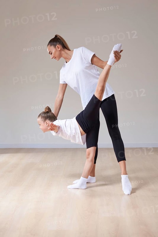 Beautiful woman teacher and a little girl perform dance movements in a bright studio. The concept of education