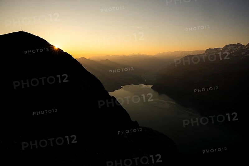 Mountain ridge with mountaineers and Swiss mountains and Lake Thun in the background at sunrise