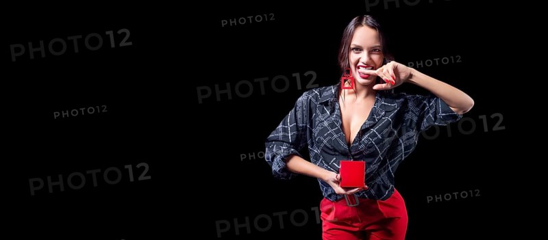 Sexy tall brunette holding a red jewelry box. She bites her finger erotically. The concept of gifts and congratulations.