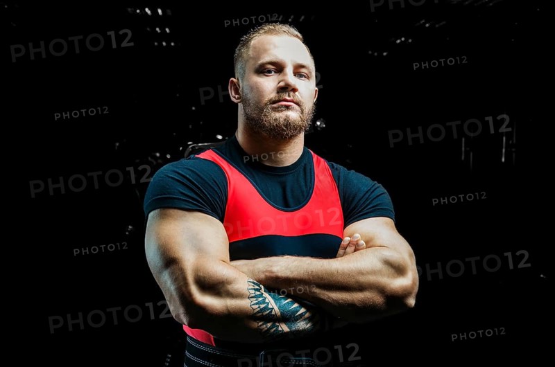 Huge powerlifter stands in front of the camera and strains his huge hands.