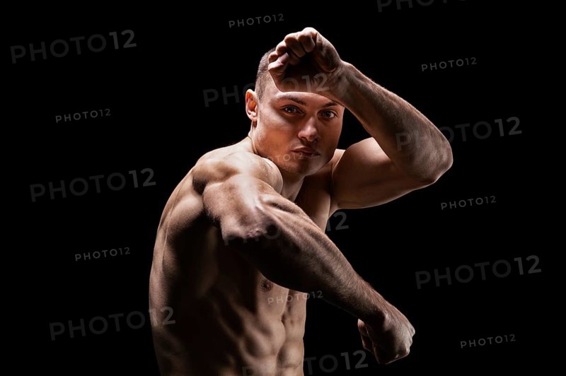 Professional boxer posing in the studio. He stands in front of the camera and elbows. The concept of sport