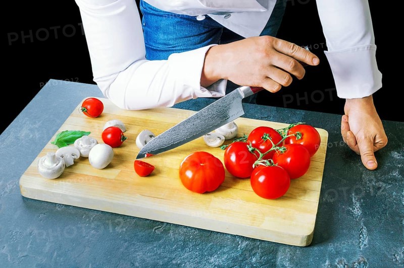 Professional chef cuts vegetables with a sharp knife from Damascus steel.