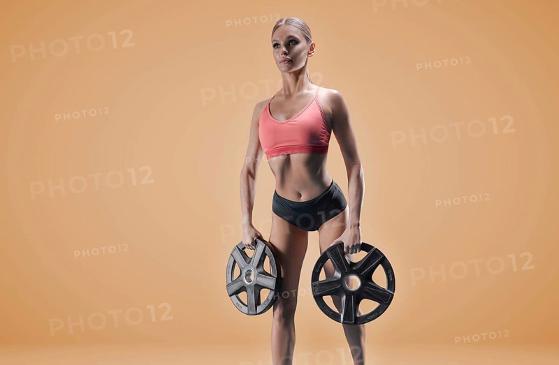 Delightful athlete posing in the studio with weights in her hands. The concept of sports