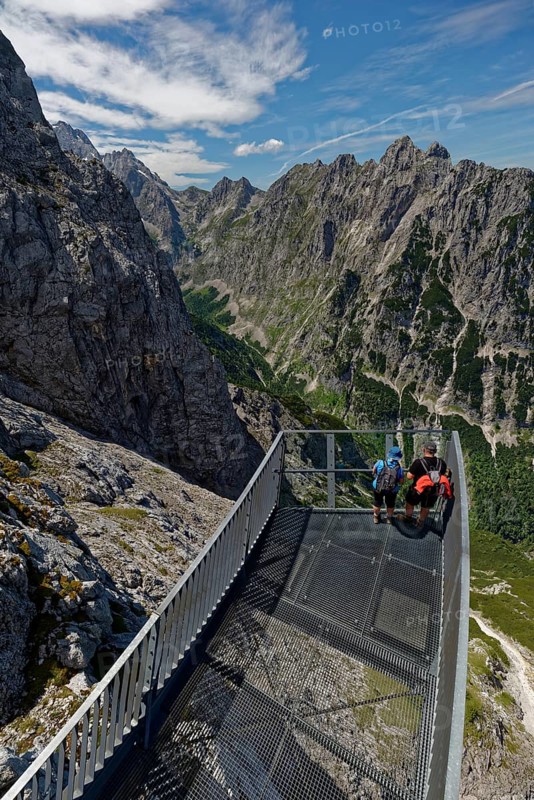 Hikers enjoy the view from a platform in a mountain range