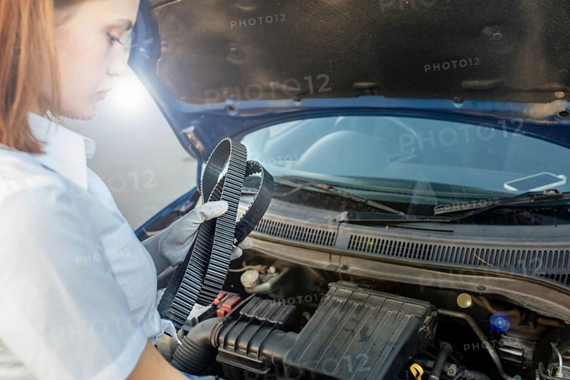 Young beautiful and hot woman auto mechanic holding a timing belt in her hands