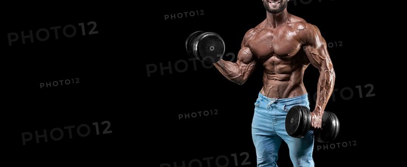 No name sexy muscular man in jeans posing on against a black background with a dumbbell. Bodybuilding and fitness concept.