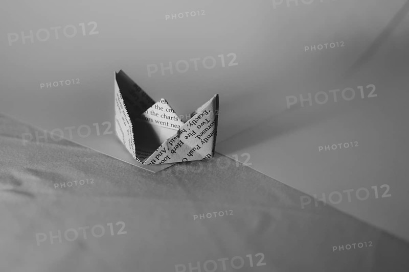 A simple paper boat in origami style on a monochrome background