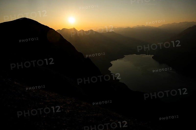 Mountain ridge with mountaineers and Swiss mountains and Lake Thun in the background at sunrise