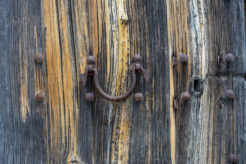 Old wooden door with aged metal door handle. Architectural textured background