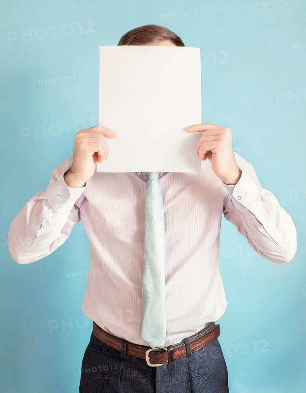 Anonymous businessman covers his head using a blank sheet to hide face expression. Incognito business person hidden behind a white empty paper