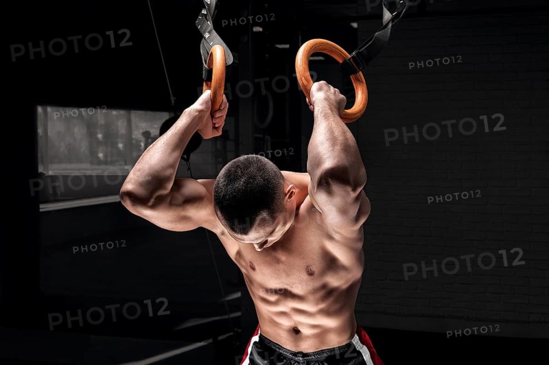 Athlete does warm-up on gymnastic rings. The concept of sport and healthy lifestyle.