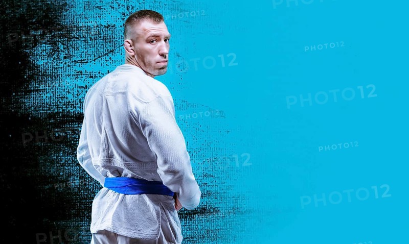 Professional wrestler is wearing a kimono. He looks over his shoulder. The concept of mixed martial arts