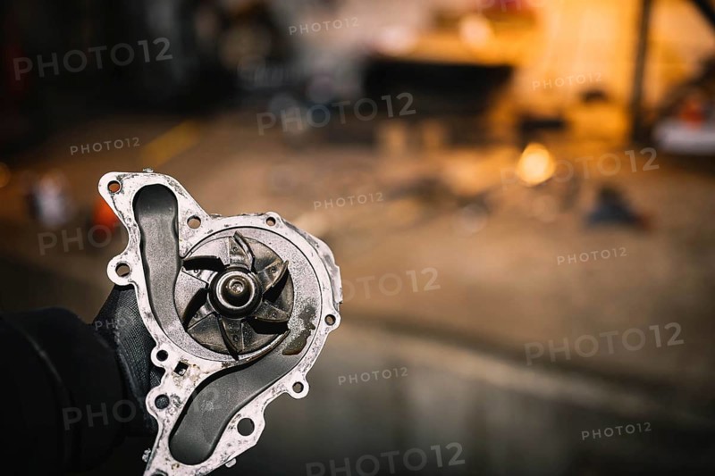 Automotive water pump of the engine cooling system in the hands of an auto mechanic