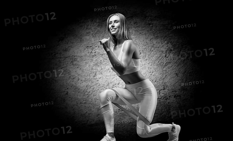 Charming girl does an exercise called lunges. Elastic band for training. The concept of fitness