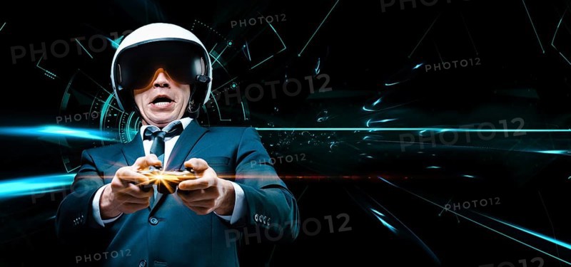 Portrait of a man in a suit and helmet of a pilot with a joystick in his hands. He enthusiastically plays a computer game. Game space. Game concept.