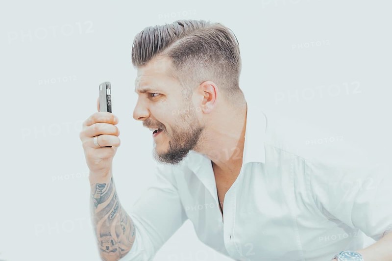 Man in a shirt looks at the smartphone screen in surprise. Concept of unsuccessful betting on games