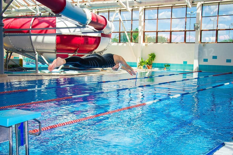 Professional athlete jumps into the water in the pool from the platform