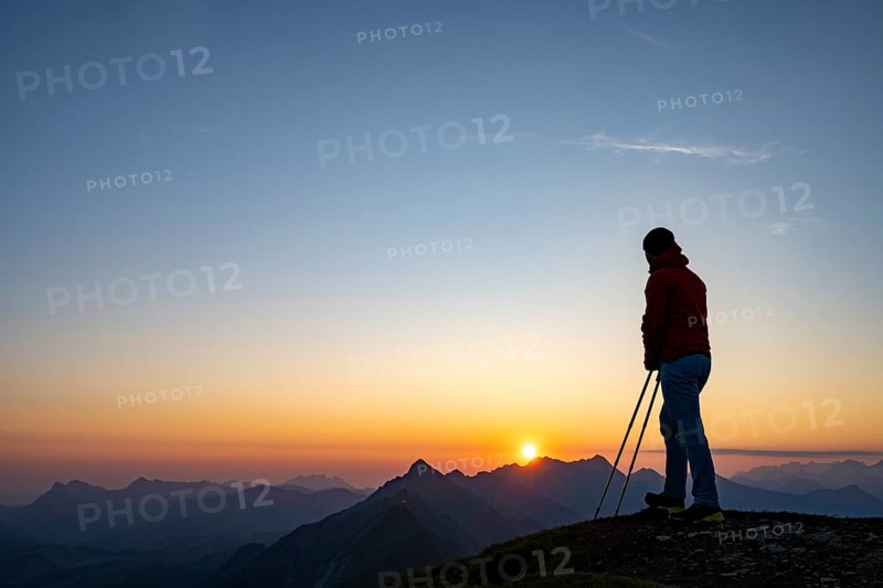 Mountaineer on mountain ridge with Rothorn peak in the background at sunrise