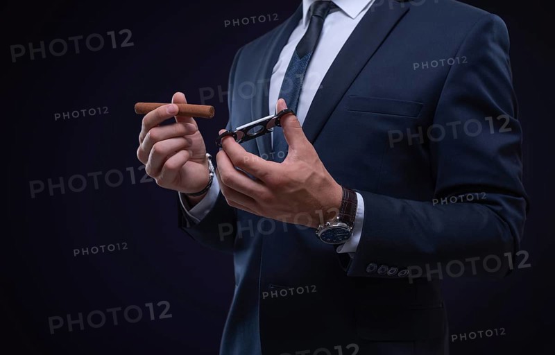 Image of an adult stylish man in a suit with a cigar. Cigar clubs concept.