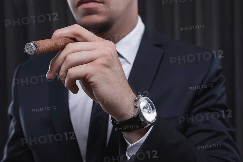Portrait of a stylish man in a suit with a cigar. Business concept.