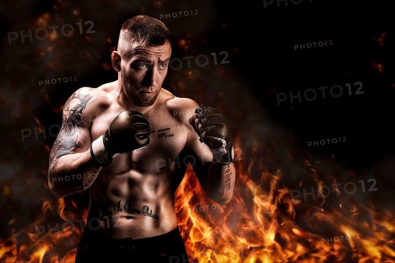 Mixed martial artist posing against the backdrop of fire and smoke. Concept of mma