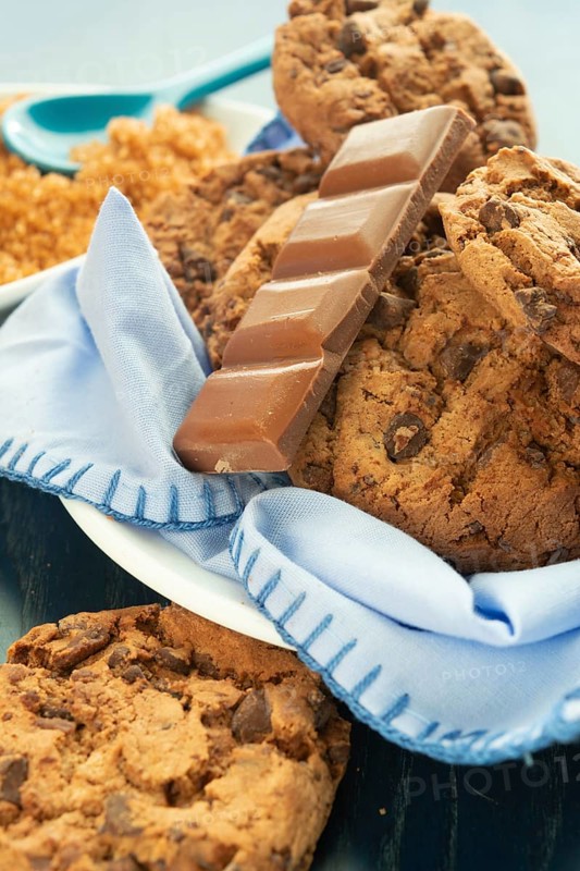 Close-up of chocolate chip cookies and a chocolate bar on a blue napkin