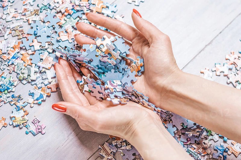 Woman holds a pile of puzzles in her hands. The concept of board educational games. Stay at home.
