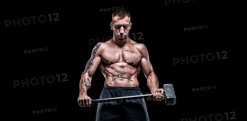 Professional sportsman stands with a sledgehammer in front of a rubber wheel. Functional training concept.