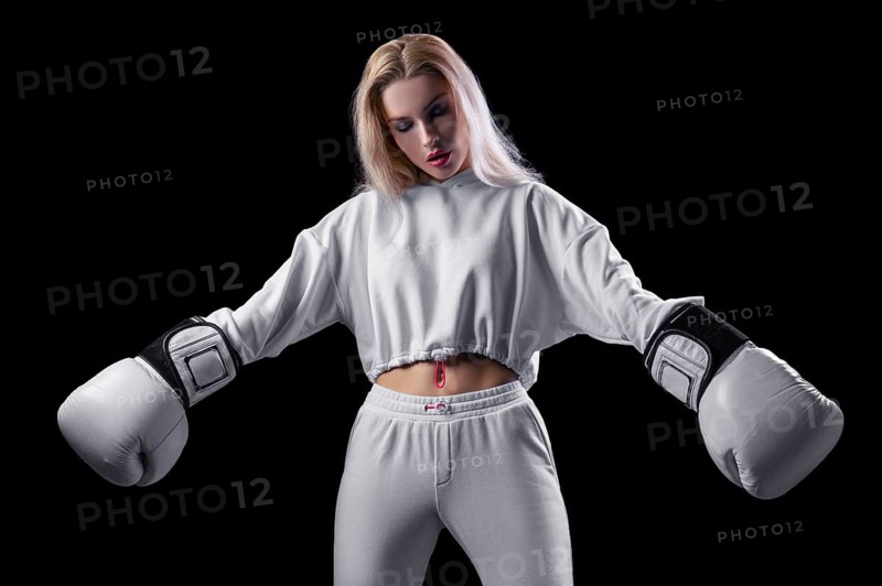 Charming girl in a white sweatshirt posing with huge white gloves. The concept of sports