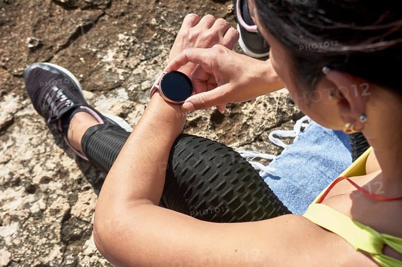 Woman sitting outdoors checking her smartwatch