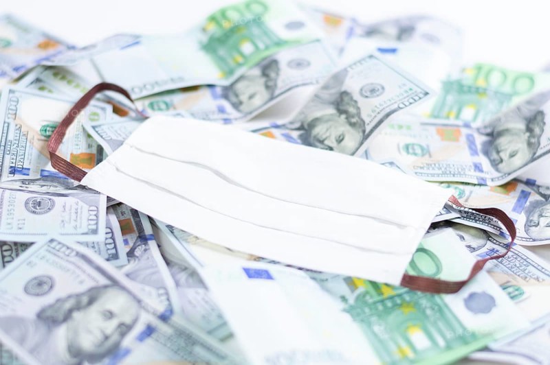 Medical mask rests on one hundred dollar bills. The concept of an epidemic