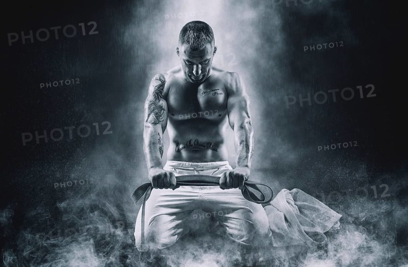 Professional athlete sits in the gym in a kimono with a blue belt. Concept of karate