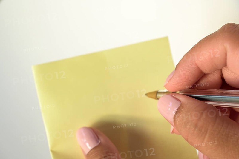Woman's hand with painted nails holding blank letter paper on pure white background