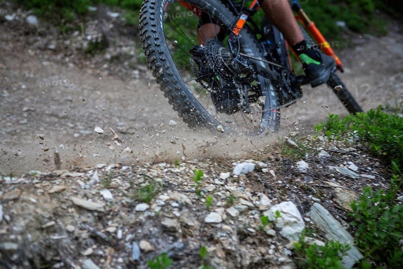 A mountain bike tyre that drifts and throws gravel into the air on the trail