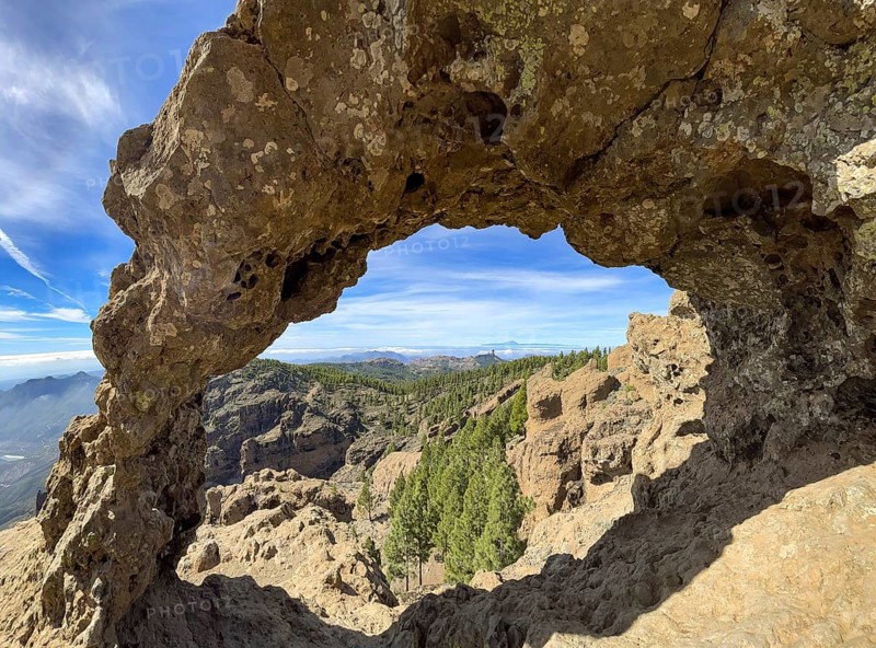 View through a rock arch to Roque Nublo and the Teide mountain peak on the neighbouring island of Tenerife