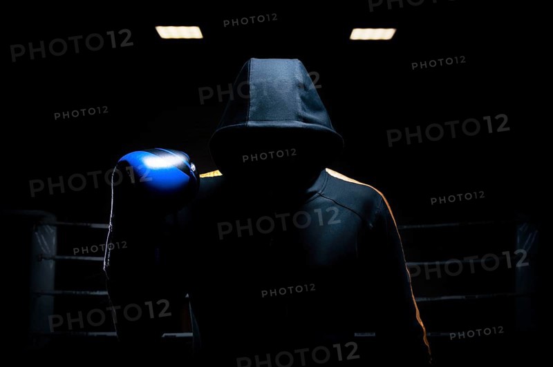 World champion in Thai boxing stands in the background of the ring with a raised blue glove. The concept of sport