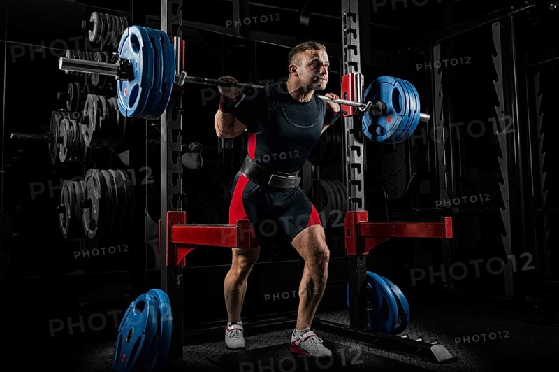 The weightlifter is preparing to lift a very heavy barbell. He exhales breathlessly and strains as much as possible before performing the exercise