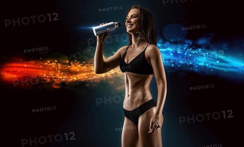 Charming young girl drinks amino acids from a shaker. Bodybuilding concept.