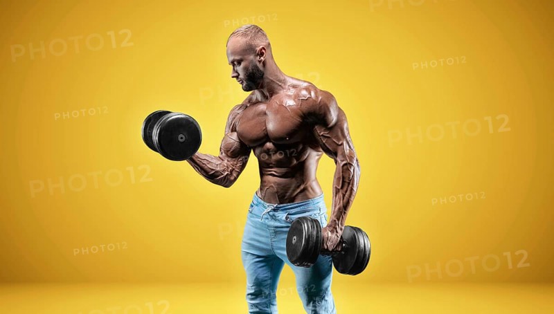 Isolated professional sportsman on a yellow background. Bodybuilding concept. Panorama. Advertising of a gym and sports nutrition.