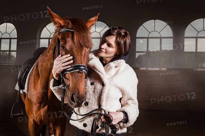 Portrait of a stylish woman hugging a thoroughbred horse. Love and care concept.