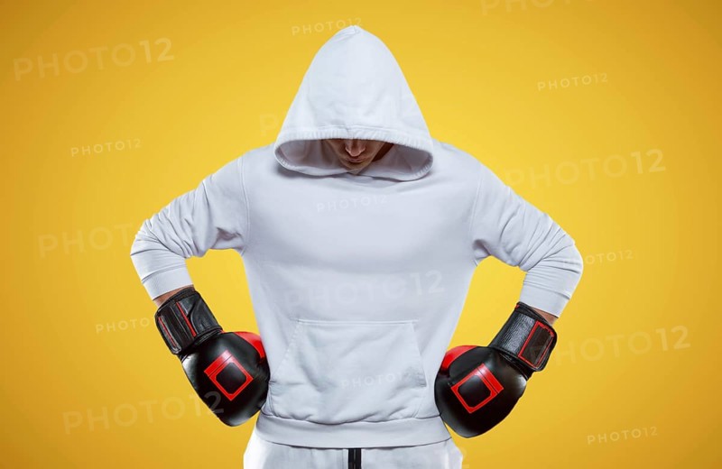 Male trainer posing in the studio with boxing gloves. White hoodie. Mixed martial arts concept. High image quality