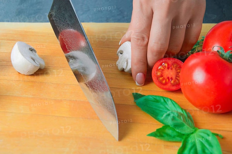 Professional chef cuts vegetables with a sharp knife from Damascus steel.