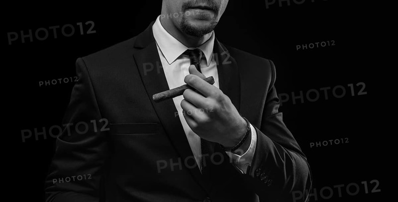 Image of an adult stylish man in a suit with a cigar. Cigar clubs concept.