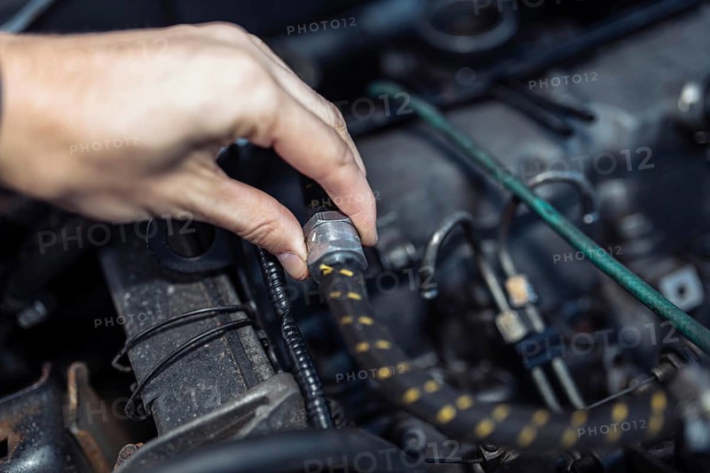 Auto mechanic regulates fuel supply with throttle cable lever