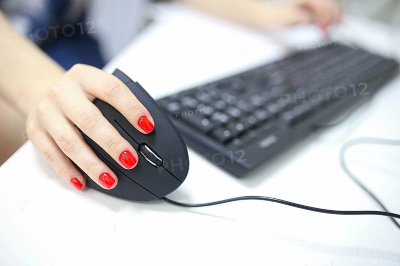 Girl's hand uses a vertical ergonomic joystick of a computer mouse. working at the computer