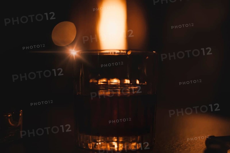 Image of a glass with a cocktail in a night bar against the background of a fiery heater. Restaurant concept