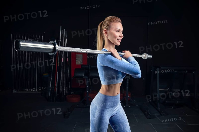 Beautiful tall blonde stands in the gym with a barbell on her shoulders. Front squats. Fitness and bodybuilding concept.