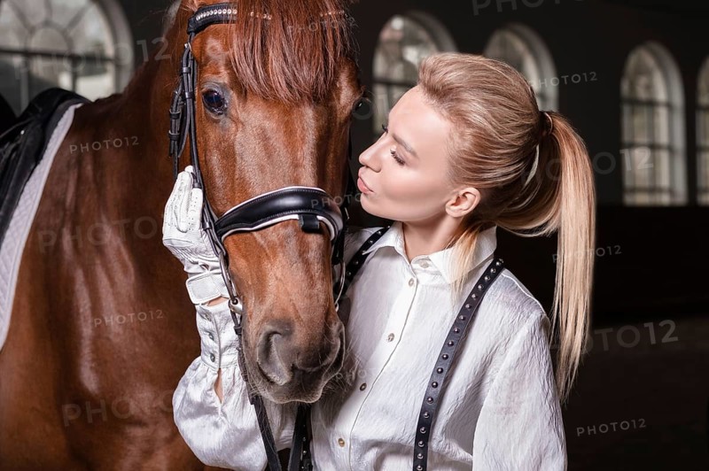 Portrait of a stylish woman hugging a thoroughbred horse. Love and care concept.